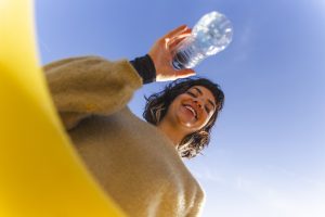 Femme jetant une bouteille en plastique dans une poubelle de tri